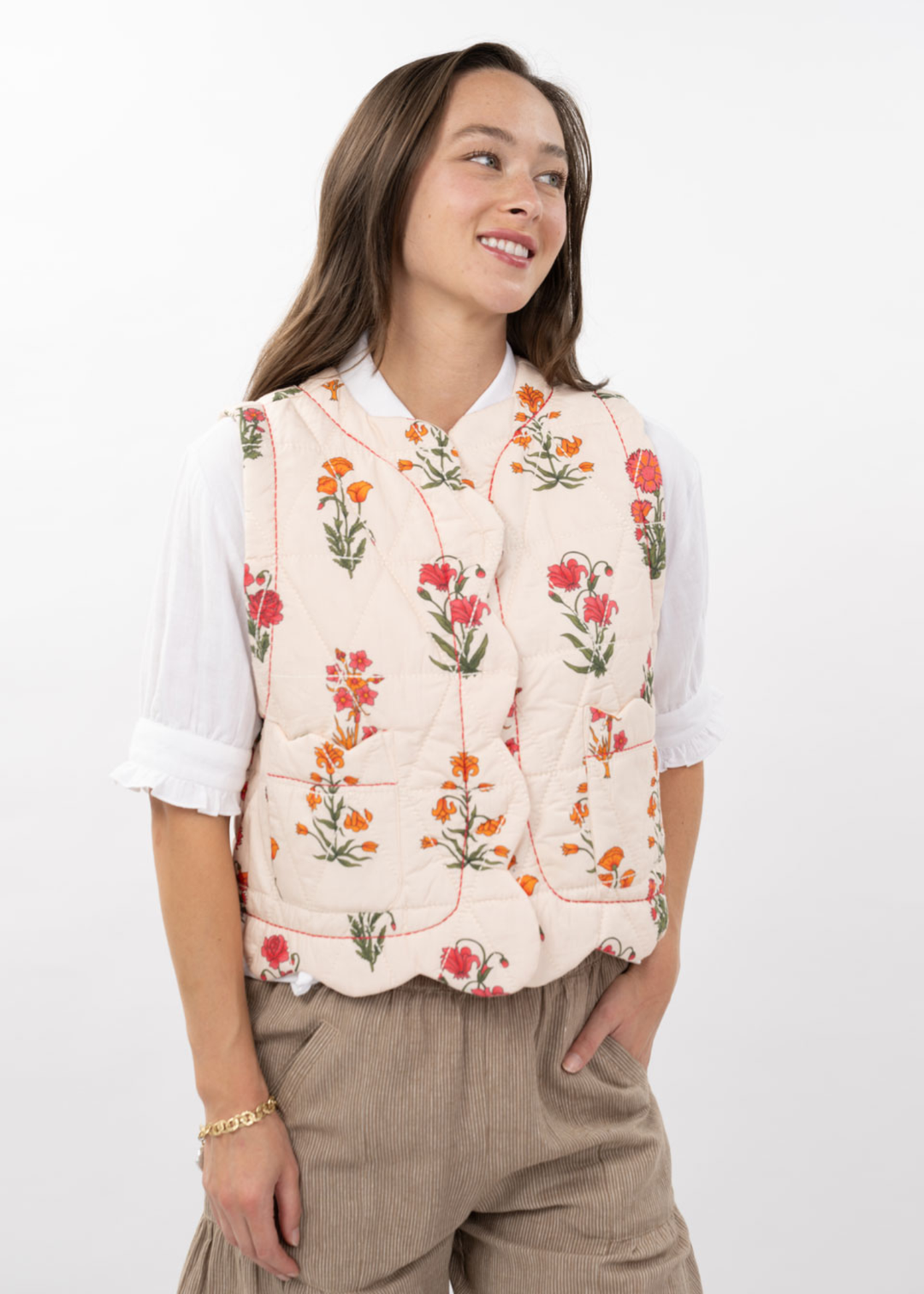 Woman wearing an ivory quilted floral vest with brown pants