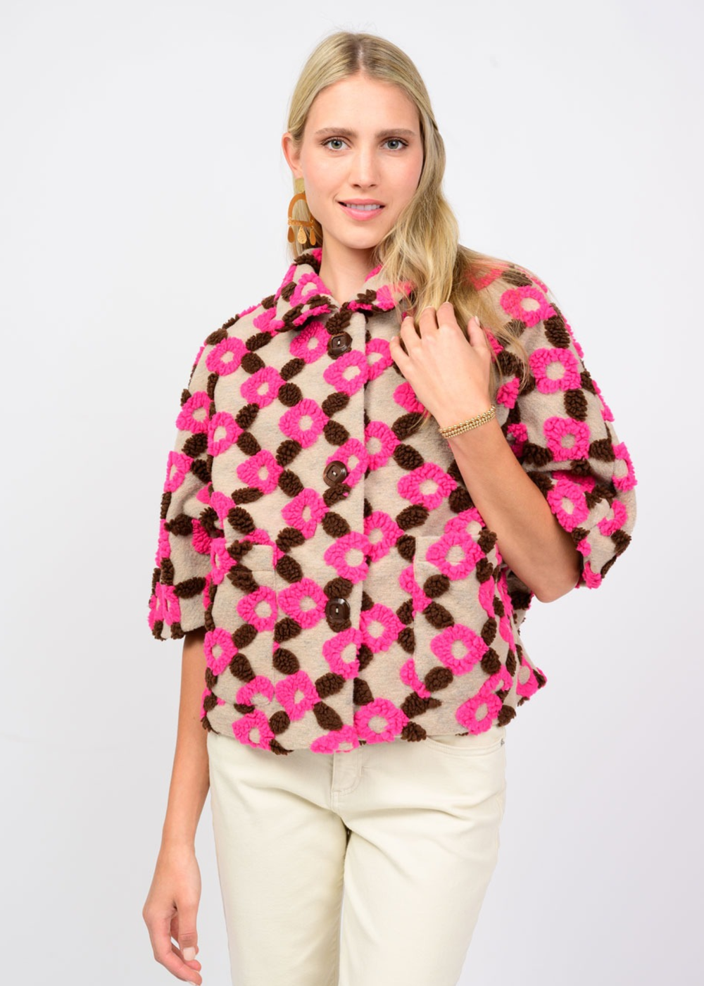 Woman wearing a tan, brown, and pink short sleeve jacket against a white background