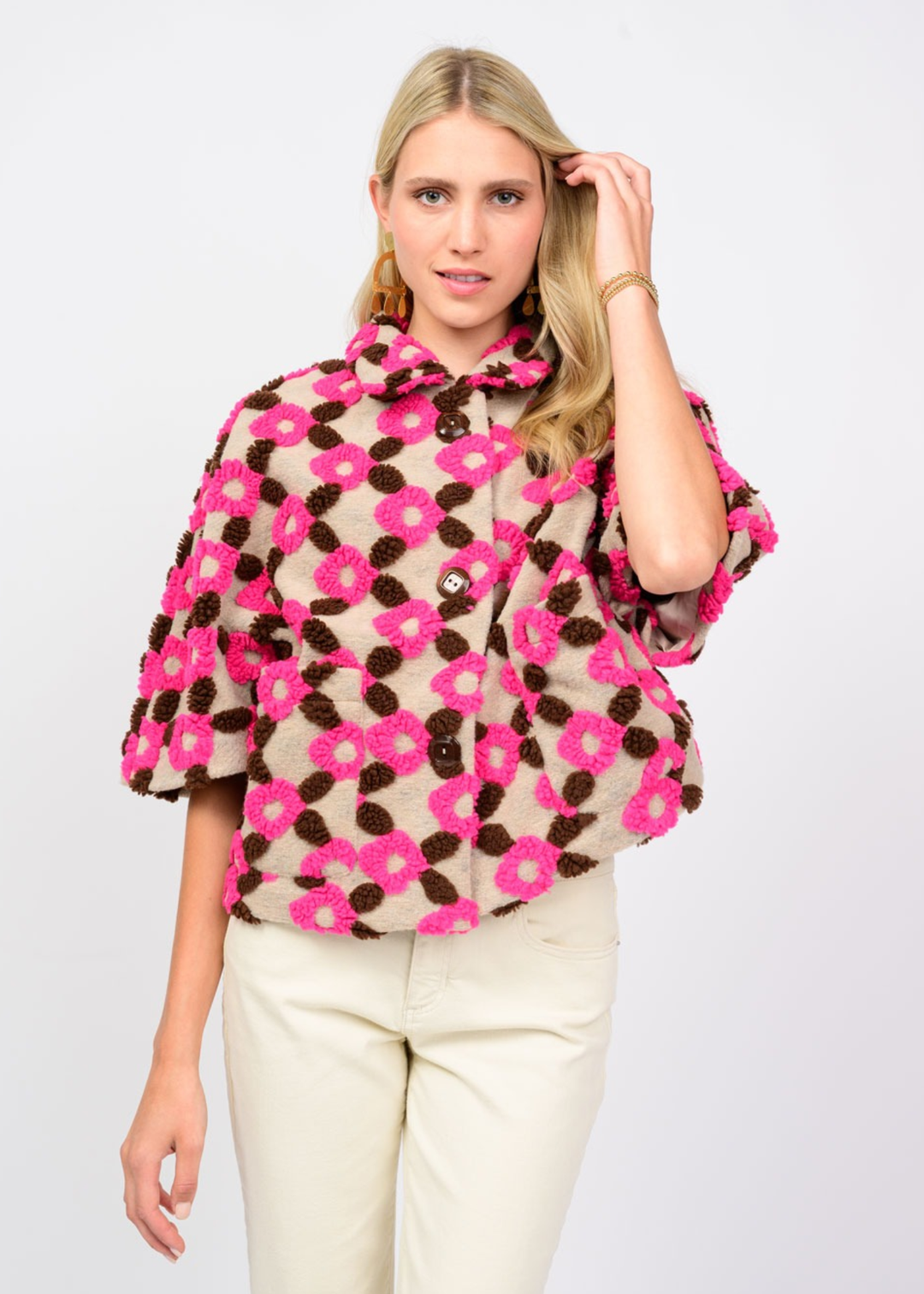 Woman wearing a tan, brown, and pink short sleeve jacket against a white background