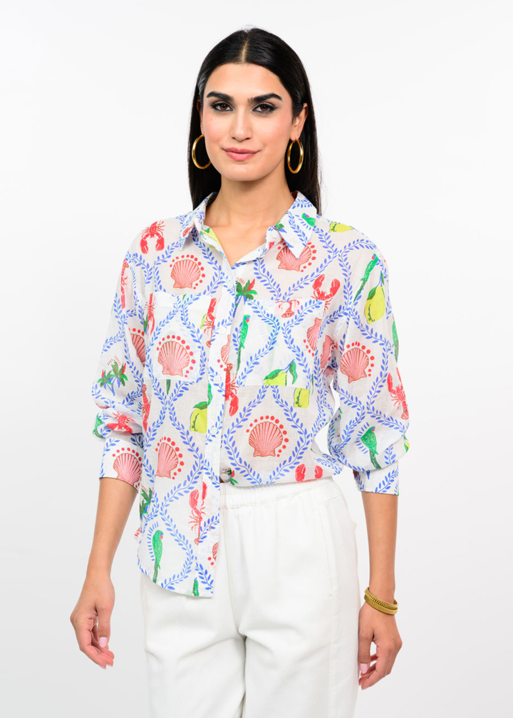 Woman wearing a white button down with a multicolor pattern with white jeans