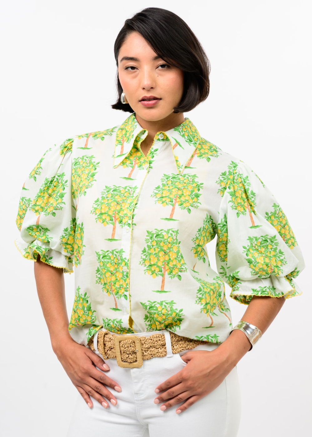 Woman wearing a white button down with a lemon tree graphic print and white pants