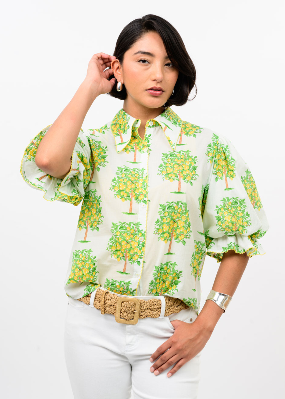 Woman wearing a white button down with a lemon tree graphic print and white pants