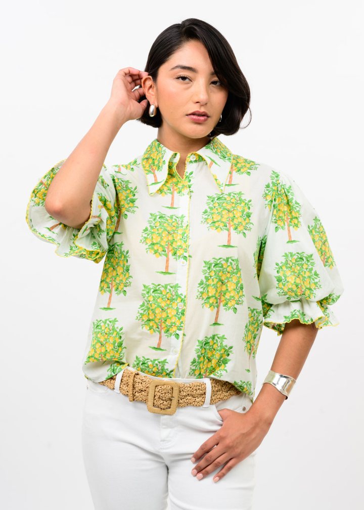 Woman wearing a white button down with a lemon tree graphic print and white pants