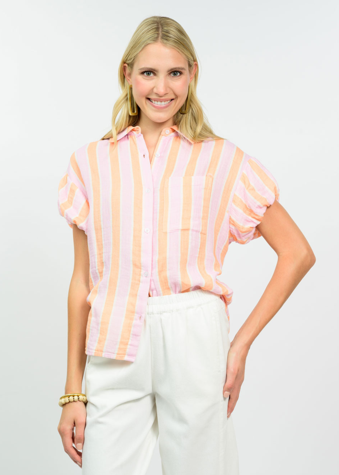 Woman wearing a tangerine striped collared button down with white pants