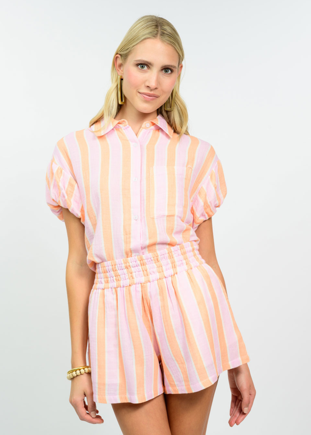 Woman wearing a tangerine striped collared button down with matching shorts