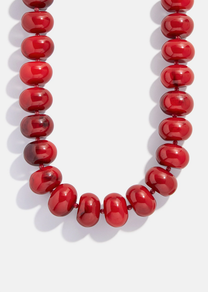 A necklace with large red beads on a white background