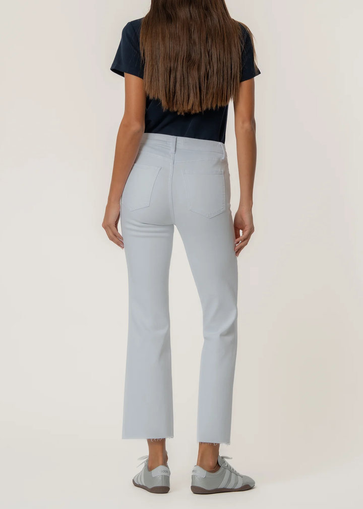 Woman turned around wearing a white flare jean with a t-shirt and sneakers