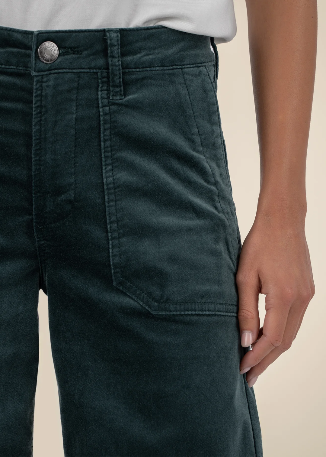 Close up of a woman wearing teal velvet jeans with a white t-shirt