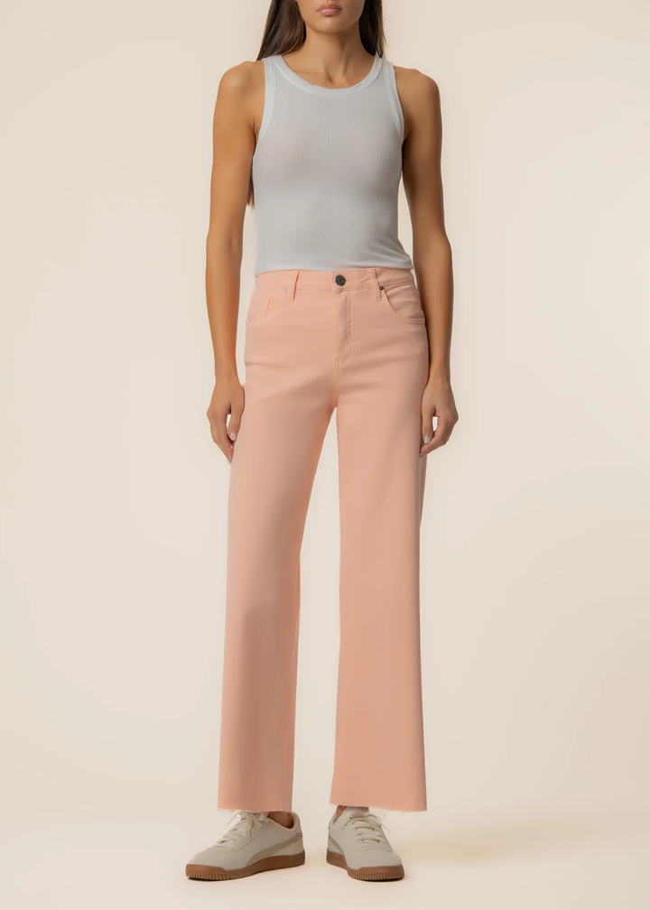 Woman wearing orange wide leg jeans with a grey tank and sneakers