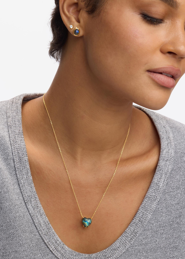 Woman wearing a heart shaped labradorite pendant necklace with matching earrings
