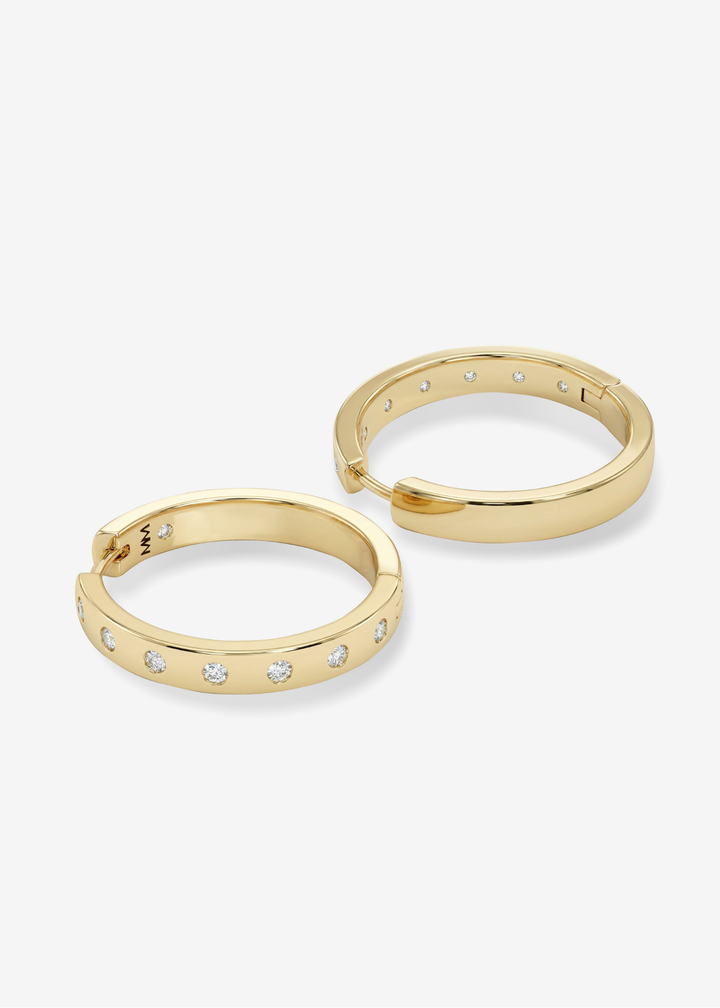 A pair of gold hoop earrings with CZ studding against a white background