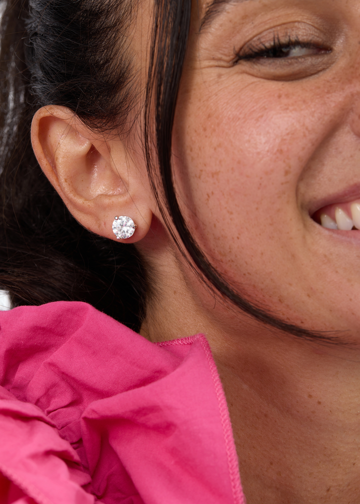 Woman wearing silver framed simulated diamond stud earrings