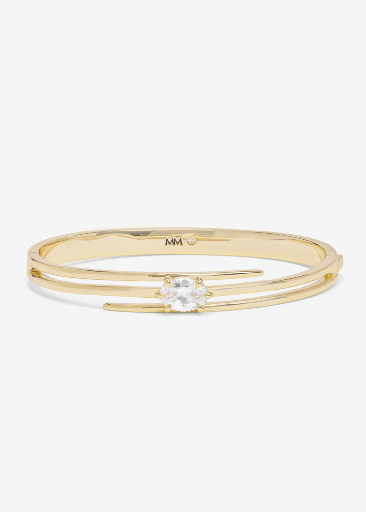 Gold lasso cuff bracelet with a diamond stud against a white background