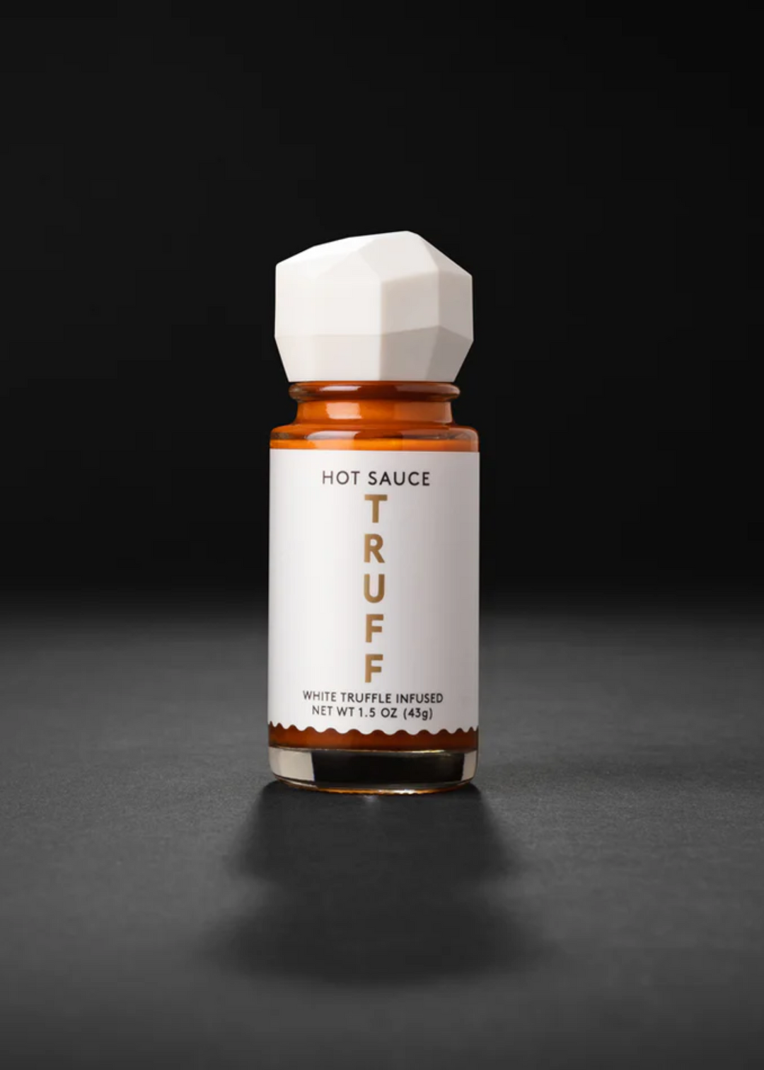 Mini white TRUFF hot sauce in white packaging on a black background