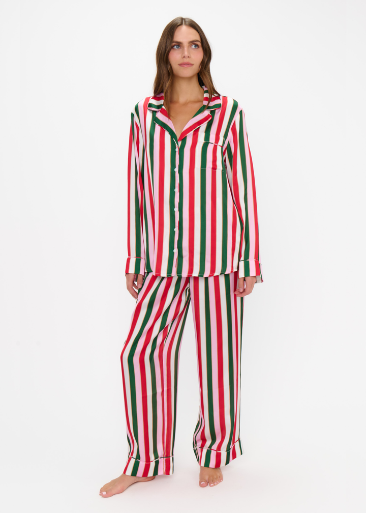Woman wearing a matching pj set with red, green, pink, and white stripes against a white background