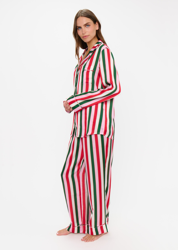 Woman turned to the side wearing a matching pj set with red, green, pink, and white stripes against a white background