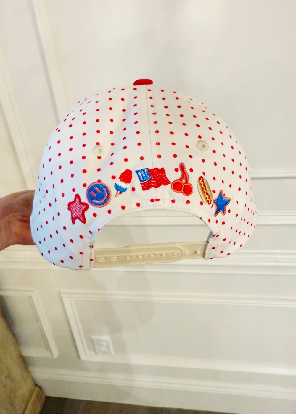 Hand holding a patterned trucker hat with summer embroidered icons