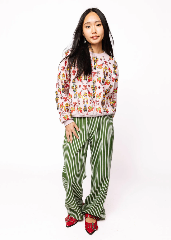 Woman wearing a sweatshirt with a nutcracker and candy cane sequin graphic