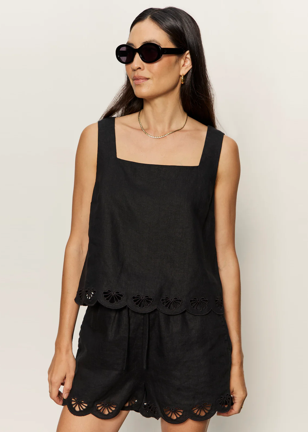 Woman wearing a black tank with an eyelet hem and matching shorts