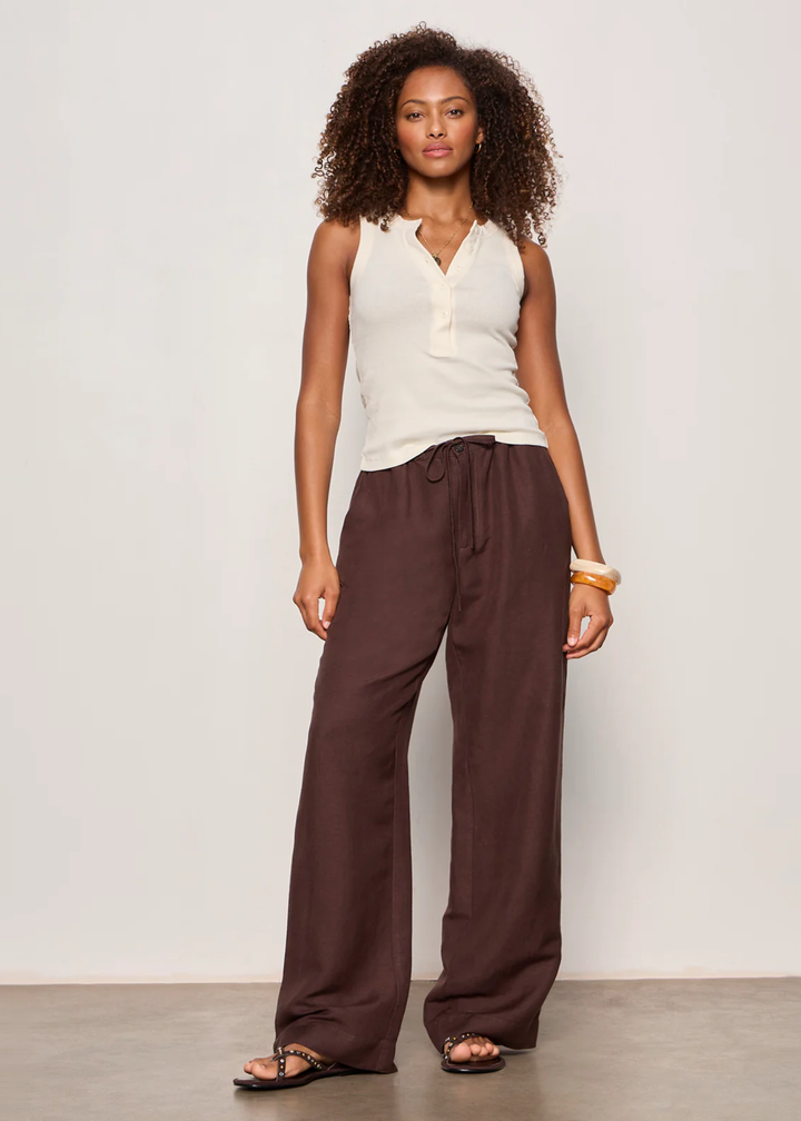 Woman wearing a cream colored tank top with brown pants