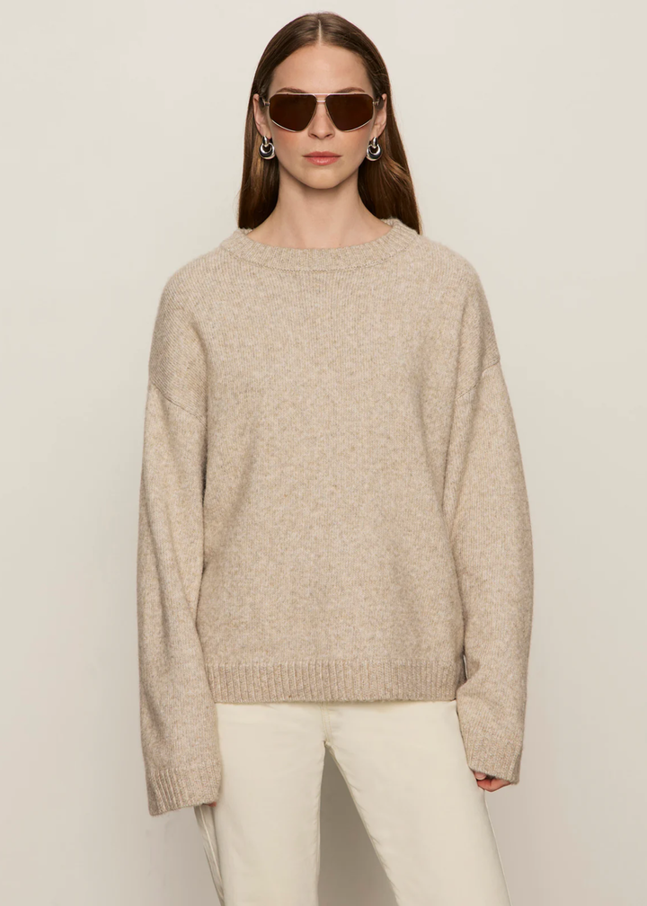 Woman wearing a tan sweater with cream jeans