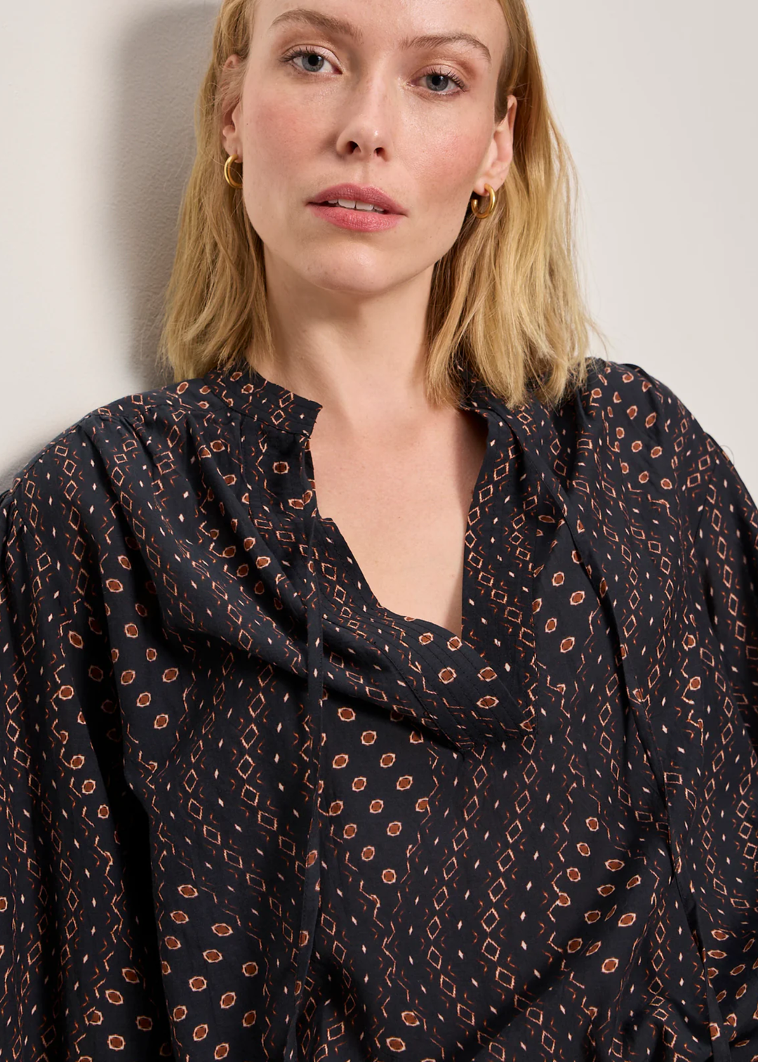 Woman wearing a black and brown patterned blouse with white shorts