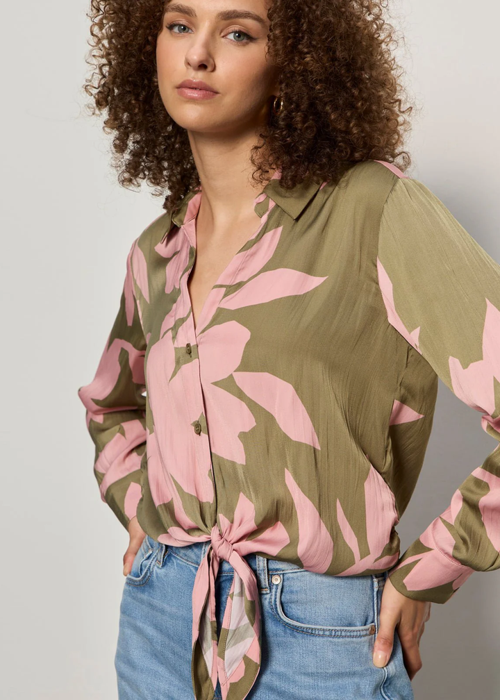 Woman wearing a green and pink floral button down tie front shirt with jeans