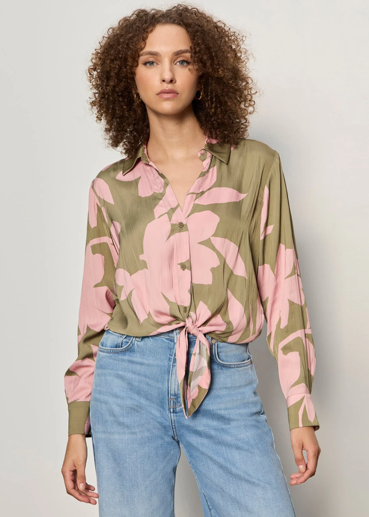 Woman wearing a green and pink floral button down tie front shirt with jeans