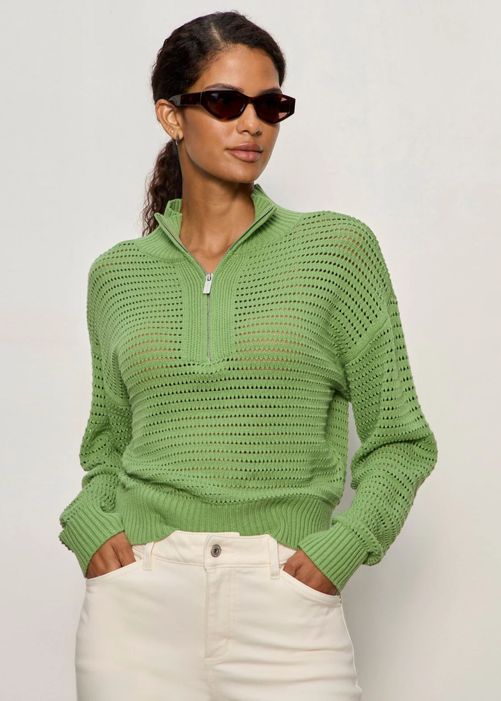 Woman wearing a green knit half zip sweater with cream jeans