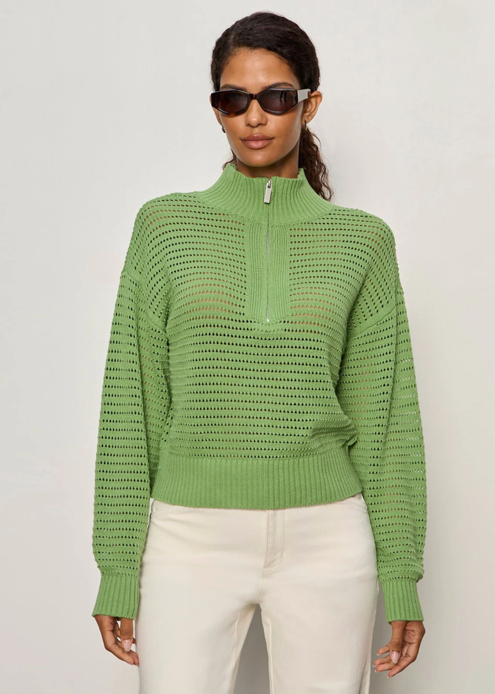 Woman wearing a green knit half zip sweater with cream jeans