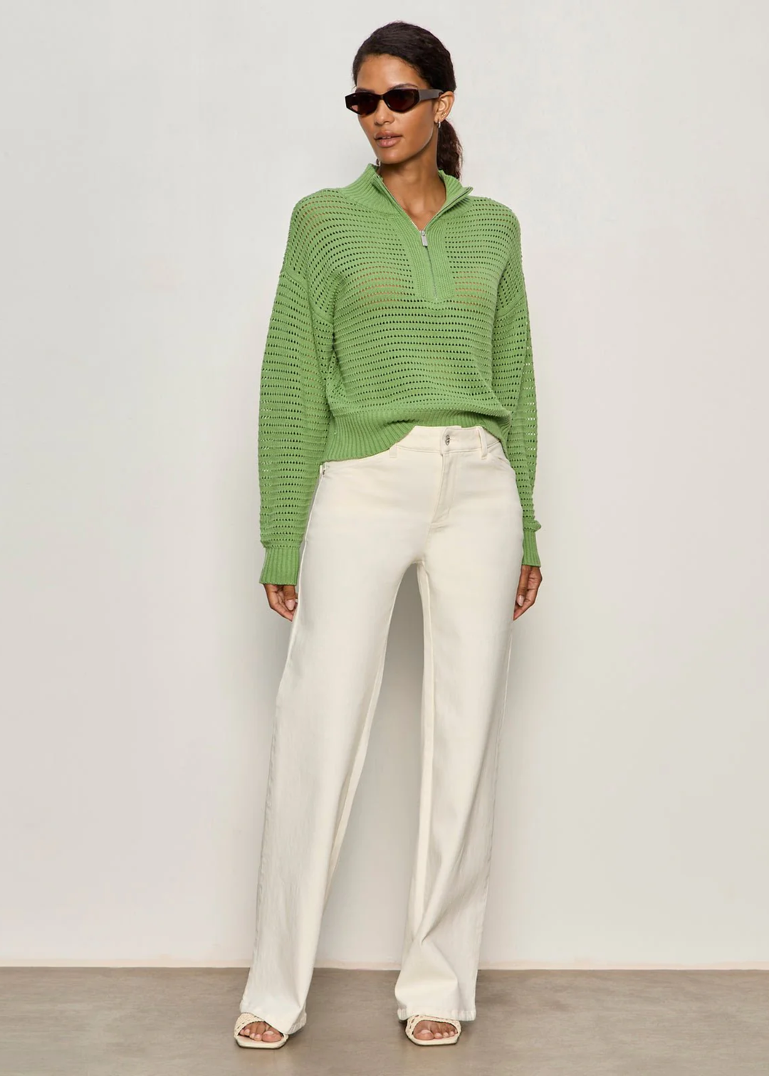 Woman wearing a green knit half zip sweater with cream jeans