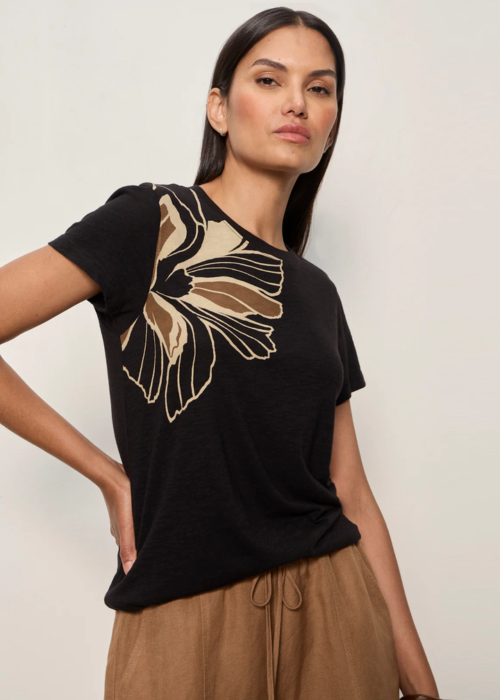 Woman wearing a black t-shirt with a large floral design and brown bottoms