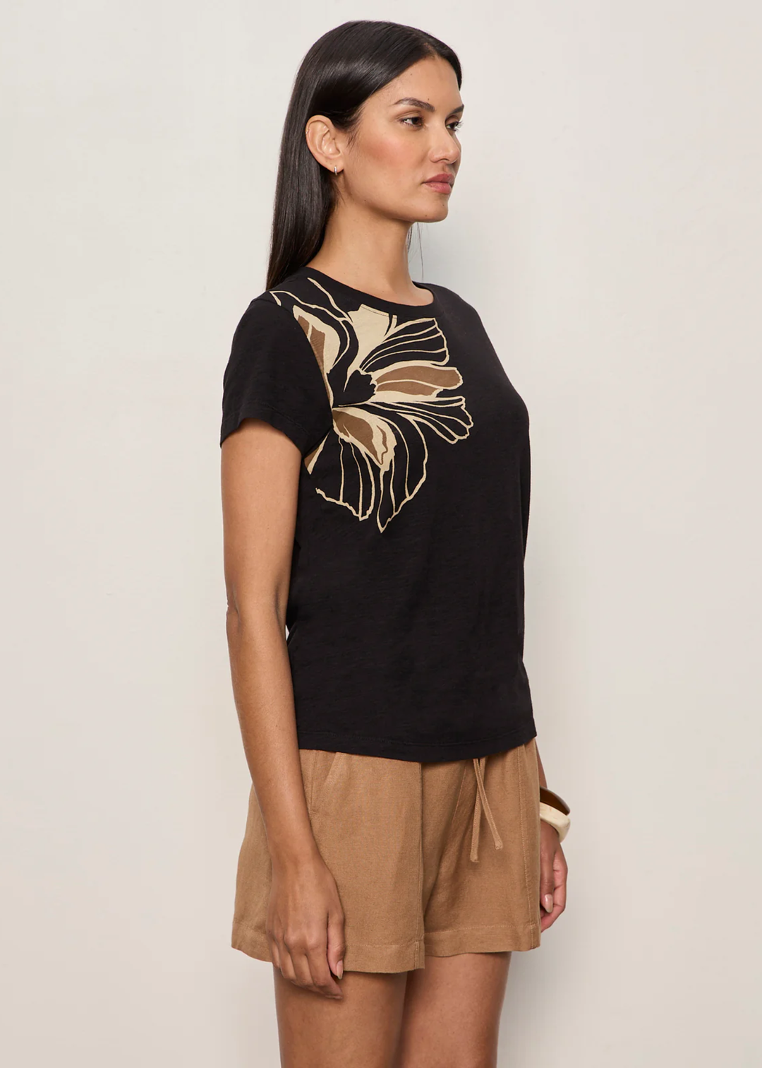 Woman wearing a black t-shirt with a large floral design and brown bottoms