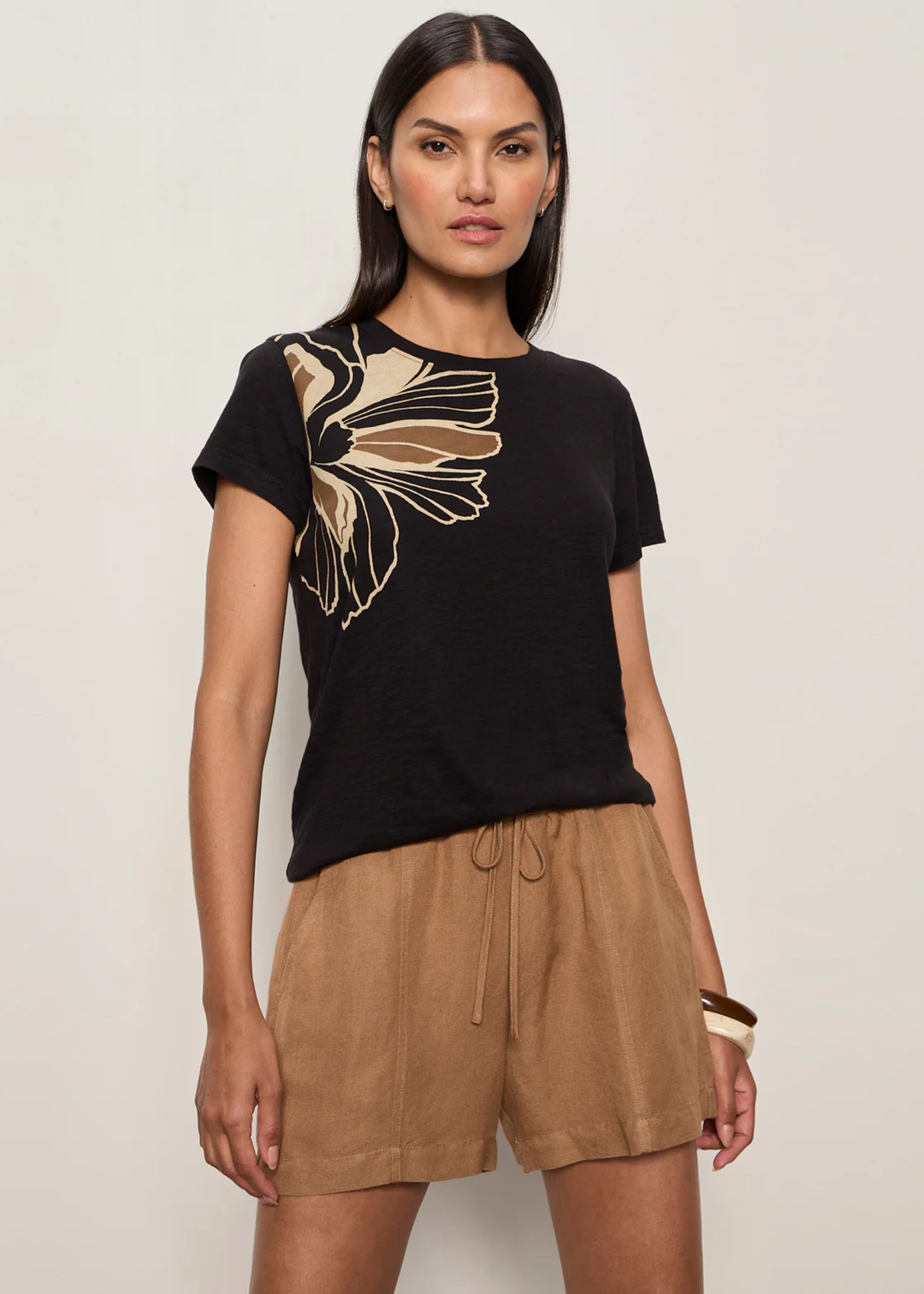 Woman wearing a black t-shirt with a large floral design and brown bottoms