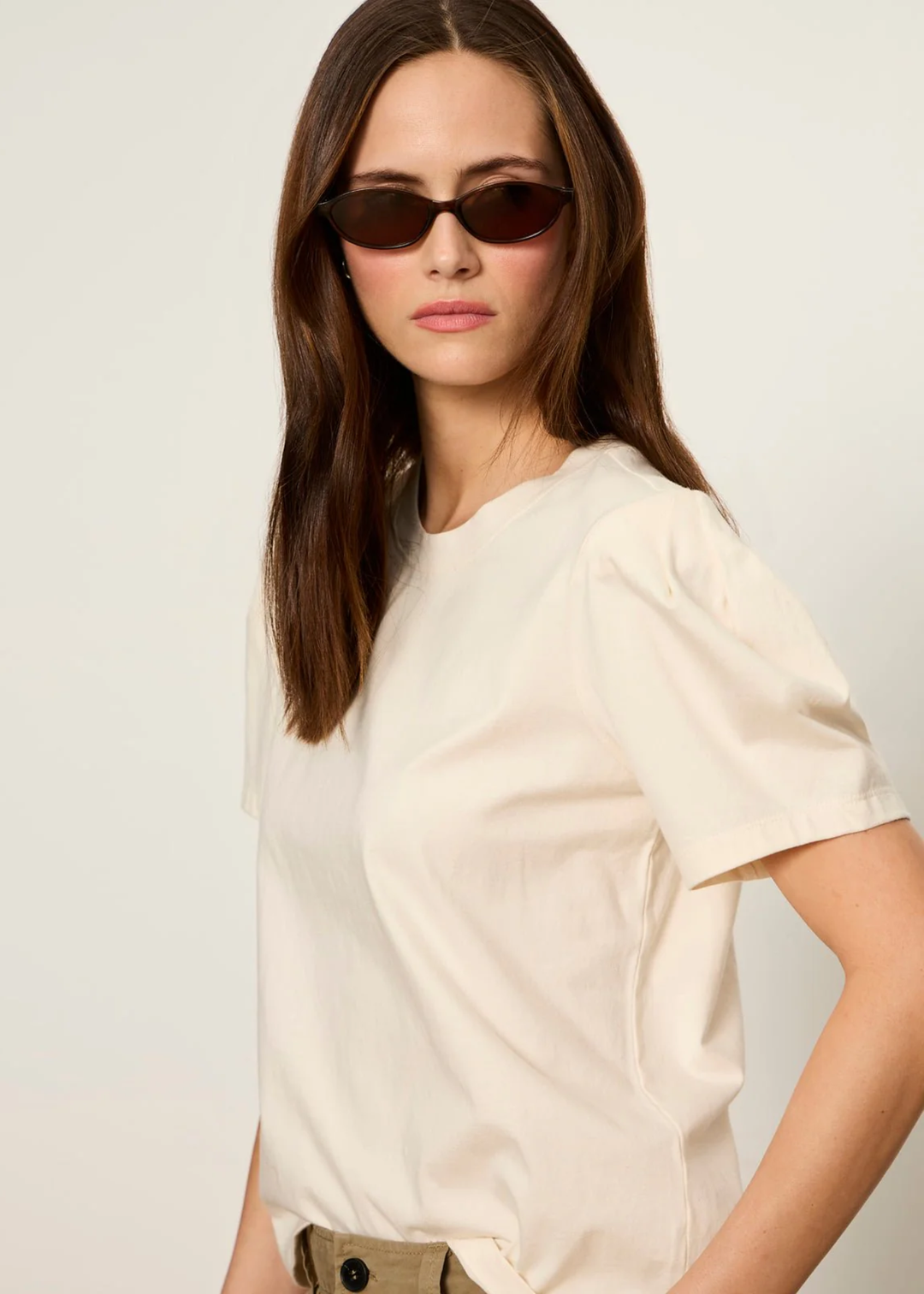 Woman wearing a cream top with tan pants and sunglasses
