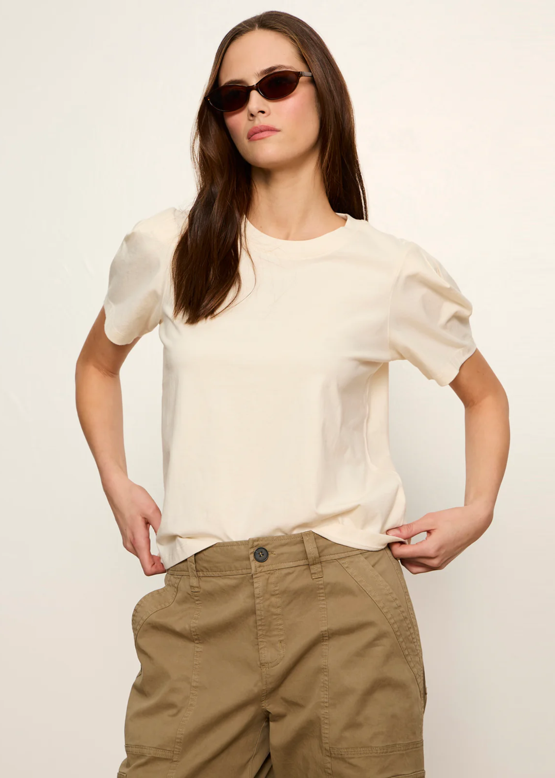 Woman wearing a cream top with tan pants and sunglasses