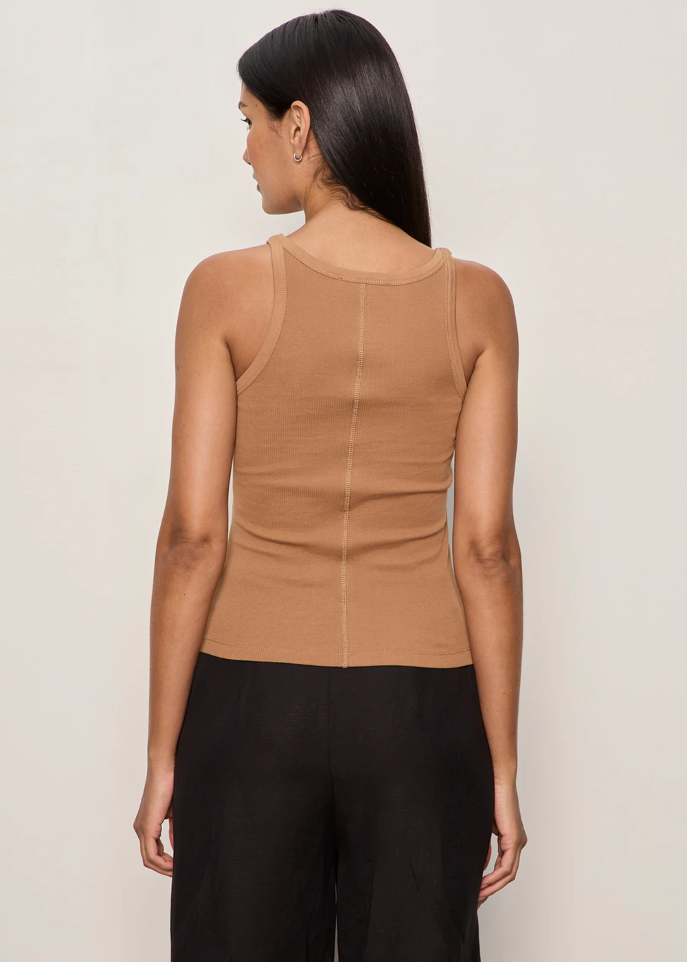 Woman turned around wearing a brown tank top with black bottoms