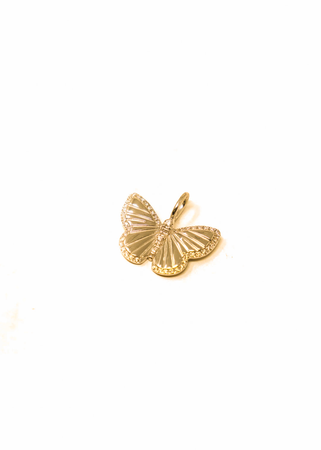 Gold butterfly charm laying on a white background