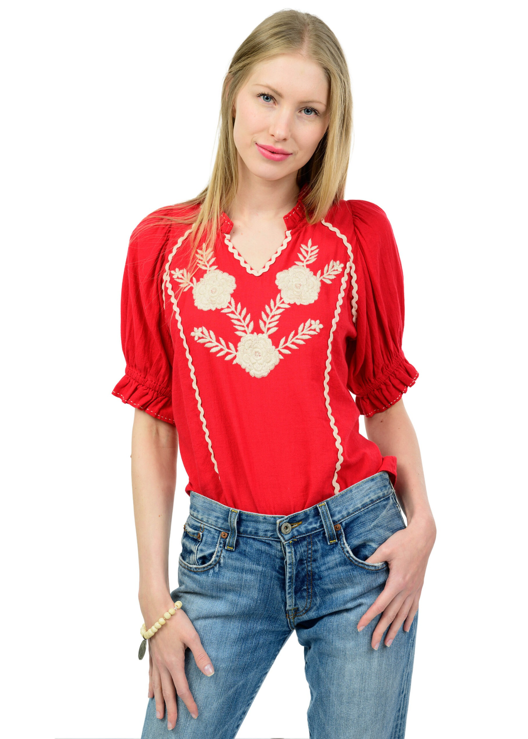 Woman wearing a red top with cream embroidery and jeans