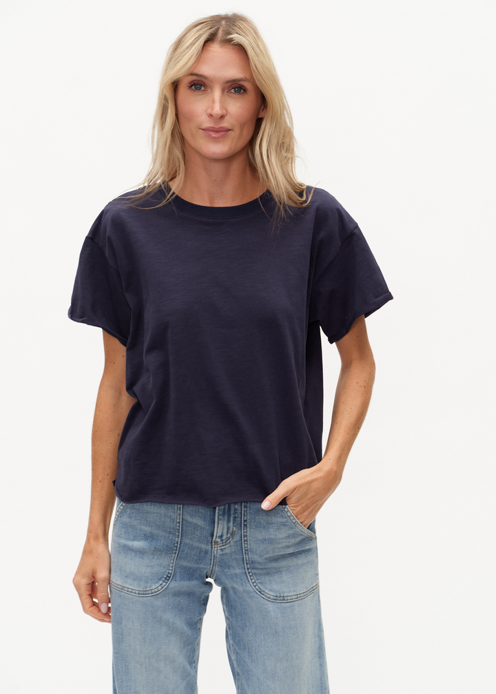 Woman wearing a navy tee shirt with buttons on the shoulders