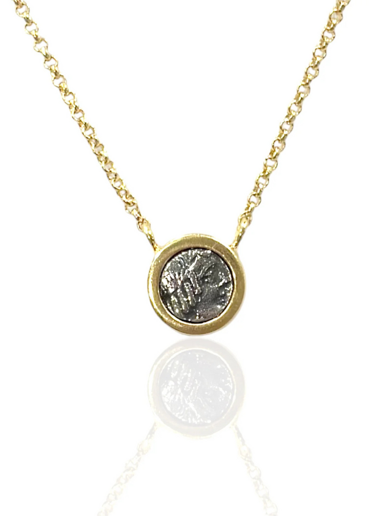 Gold necklace with a silver coin pendant on a white background