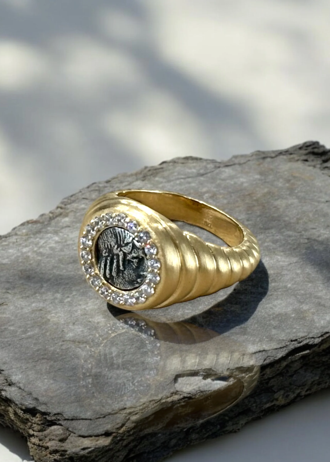 Gold scalloped ring with a silver coin framed in CZ's sitting on a rock