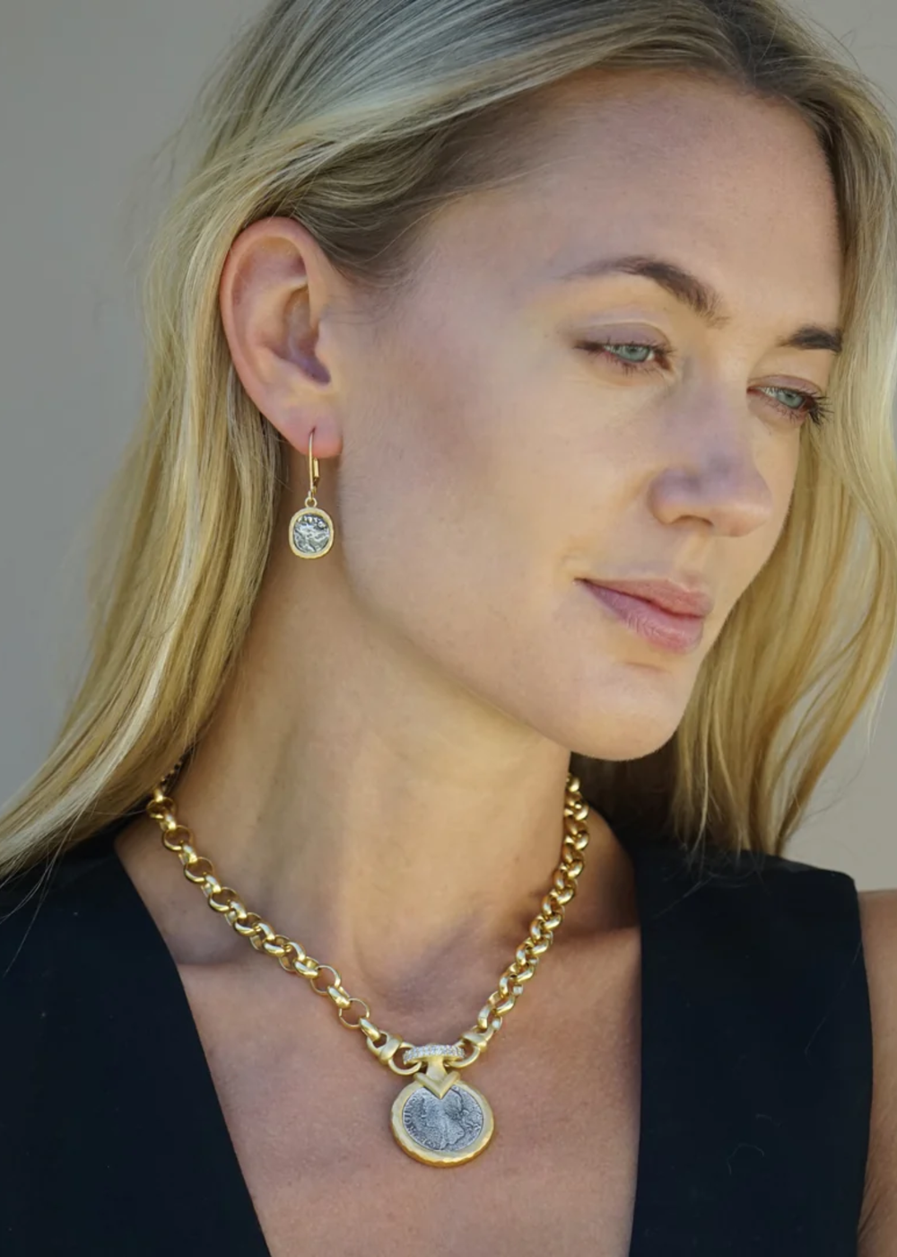 Woman wearing a gold chain necklace with a silver coin pendant