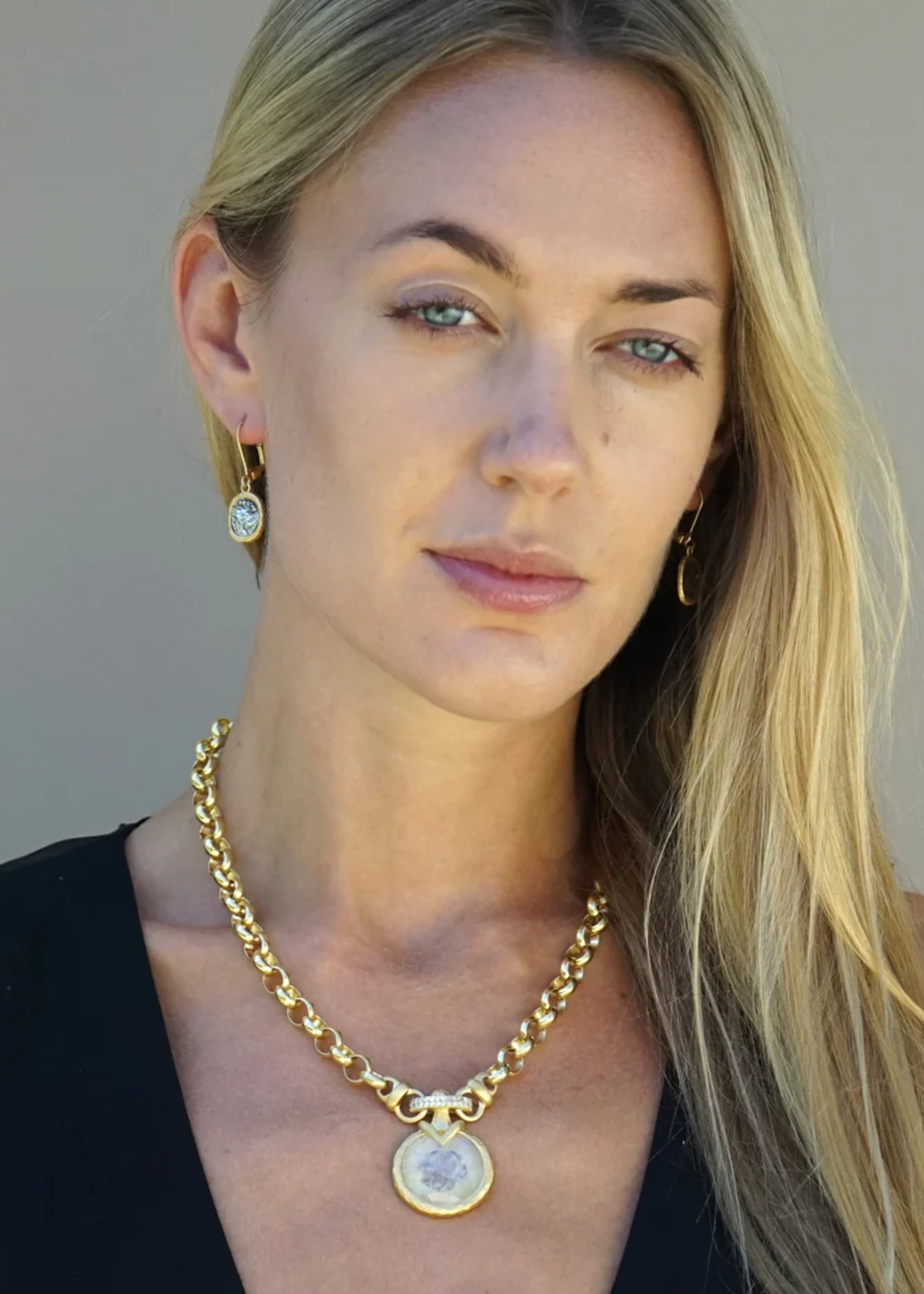 Woman wearing a gold chain necklace with a rainbow moonstone pendant