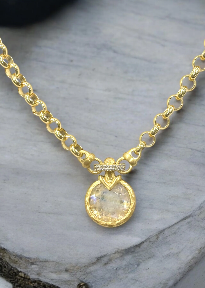 Gold chain necklace with a rainbow pendant on a grey background