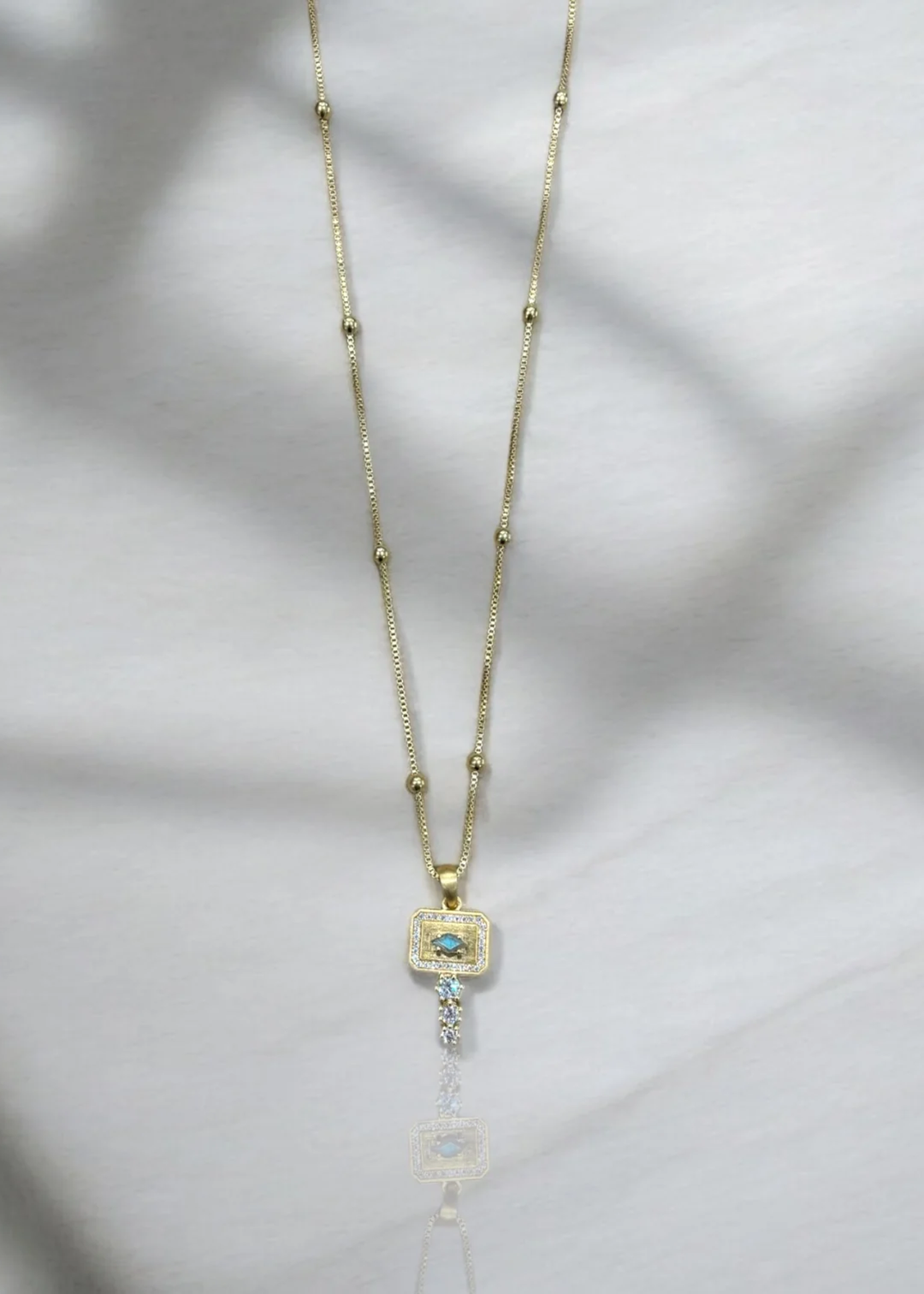 Gold pendant necklace with CZ details on a white background
