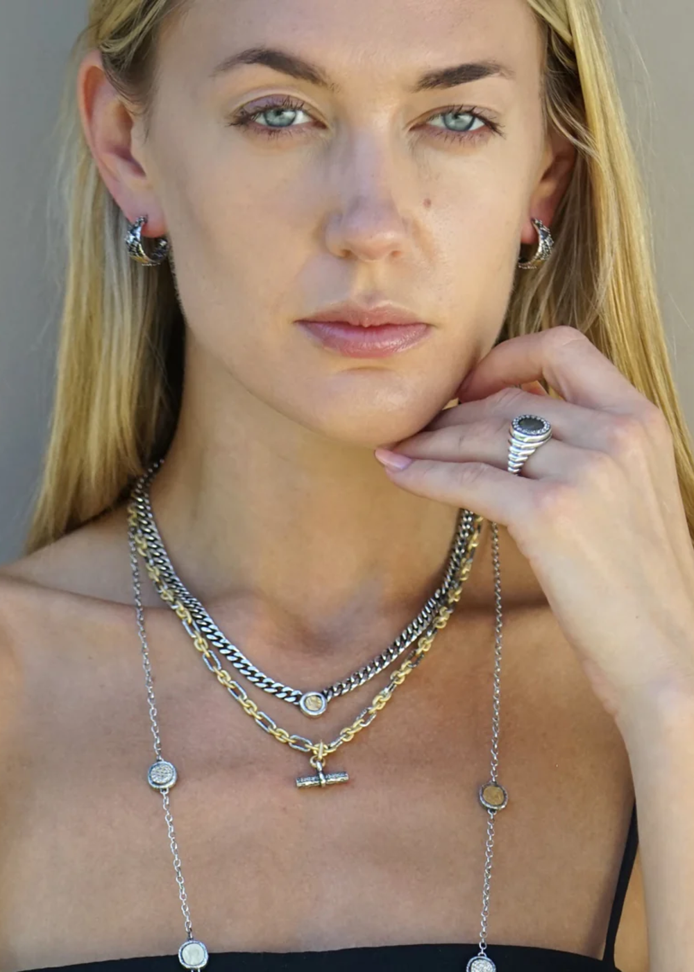 Woman wearing silver layered necklaces with a silver chain necklace with gold coins