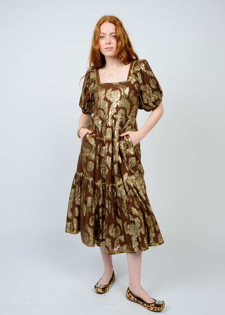 Woman wearing a brown midi dress with a gold floral pattern