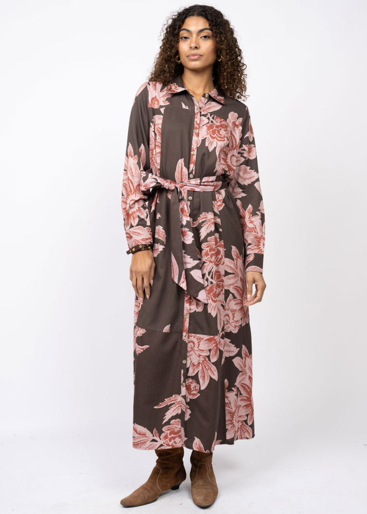 Woman wearing a brown maxi dress with a pink floral print and belt