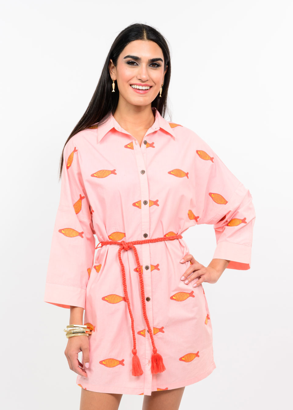 Woman wearing a blush colored dress with a fish pattern and a pink belt